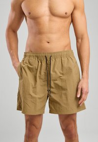 Shorts da bagno khaki con vita elastica, cordoncino e tasche laterali. Realizzati in tessuto leggero e testurizzato. Design casual.