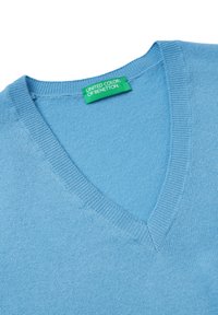 Vaaleansininen v-aukkoinen neulepaita pehmeästä neuloksesta. Pinta on sileä, hienoraitaiset reunat. Lipussa lukee "United Colors of Benetton."