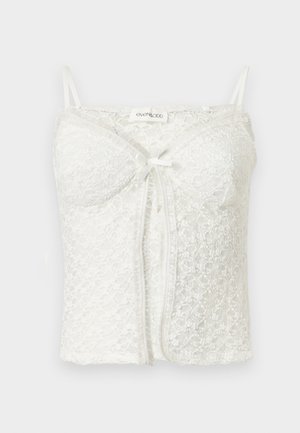 Camisole courte en dentelle blanche avec fines bretelles, bonnets intégrés, détail nœud à l'avant et motif floral en dentelle.