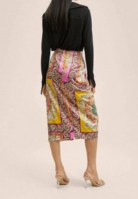 Jupe midi en satin avec un design paisley vibrant en jaune, rose et violet. Texture lisse avec une silhouette droite et taille haute.