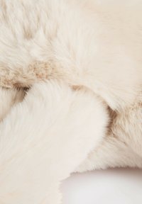 Pelliccia finta in morbido e pallido beige, con una consistenza spessa e soffice, caratterizzata da leggere variazioni e un aspetto liscio. Senza motivi o accenti prominenti.