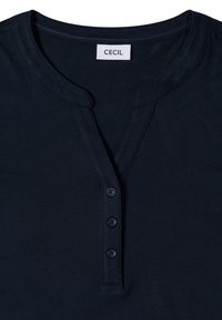 Chemise bleu marine avec un col rond échancré, trois boutons assortis le long de la patte de boutonnage, et une étiquette de marque "CECIL" à l'intérieur du col.