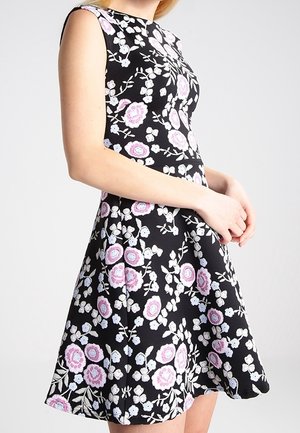 Zwarte bloemenjurk met een aansluitend lijfje, kapmouwen en een uitlopende rok, versierd met roze en witte bloemenpatronen.