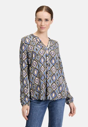 Langärmlige Bluse in einer blauen Farbe mit geometrischem Diamantmuster in Beige, Burgunderrot und Creme; V-Ausschnitt mit Knöpfen und gerüschten Manschetten.