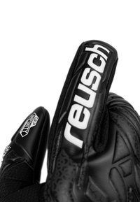 Schwarze Torwart-Handschuhe mit geprägten Mustern, mit "Reusch"-Logo in Weiß. Sie verfügen über eine strukturierte Grifffläche an den Fingern und einen flexiblen Handgelenkbereich.