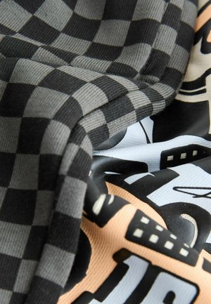 Karierter Stoff in Schwarz und Grau, kombiniert mit einem gemusterten Material mit sanften Farben wie Pfirsich und Hellblau sowie grafischen Designs.