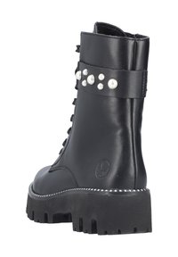 Bottines noires en cuir avec une semelle épaisse, présentant un design à lacets, des accents de perles asymétriques et une surface texturée.