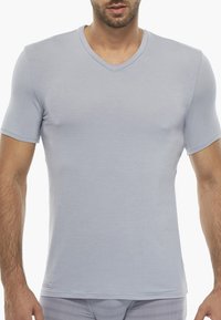 T-shirt azzurro chiaro a maniche corte con scollo a V realizzato in tessuto morbido. Design aderente con una texture liscia. Costruzione semplice e priva di decorazioni.