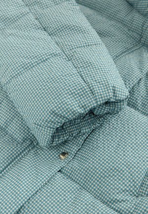 Steppjacke im hellblauen Vichy-Karos, mit weicher Textur, voluminösem Design und sichtbarem Metall-Druckknopfdetail.