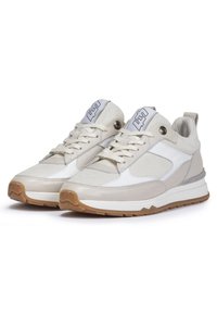 Baskets blanches et beiges combinant cuir lisse et tissu texturé, avec un bout rond et une semelle en caoutchouc. Logo distinctif sur la languette.