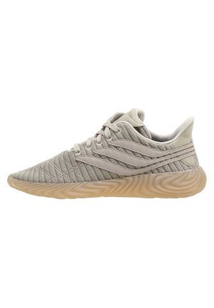 Lysegrå strikket atletiksneaker med tekstureret beige sål og tre bølgeformede side striber, vist i højre sideprofil.
