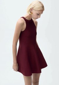 Bordo halter haljina bez rukava s uskim gornjim dijelom i lepršavom suknjom. Izrađena od glatkog materijala, s visokim izrezom i bez vidljivih uzoraka.