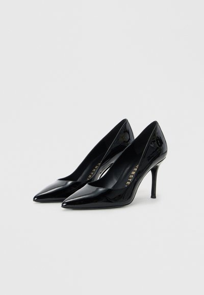 Chaussures à talons hauts en cuir verni noir avec des orteils pointus et un design décolleté, présentant une silhouette élégante et des talons fins de 10 cm.