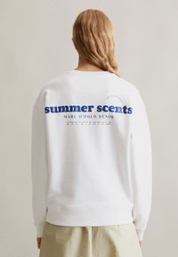 Witte sweatshirt met blauwe tekst waarin staat "zomerse geuren" en "MARC O'POLO DENIM" op de achterkant. Zacht materiaal met een ontspannen pasvorm.