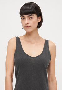 Top gris sin mangas con un escote en V profundo, tejido texturizado y un diseño ajustado. Presenta tirantes estrechos y una costura vertical en la parte delantera.