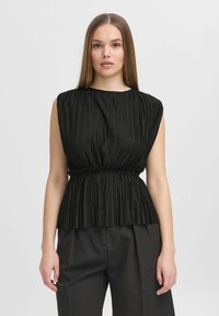 Top plissettato nero con scollatura rotonda, design senza maniche e vita elastica arricciata, abbinato a pantaloni neri dal taglio morbido.