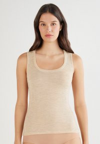 Top in beige realizzato in un tessuto morbido e leggero, con scollo rotondo e spalline sottili. Presenta un aspetto testurizzato e leggermente a coste.