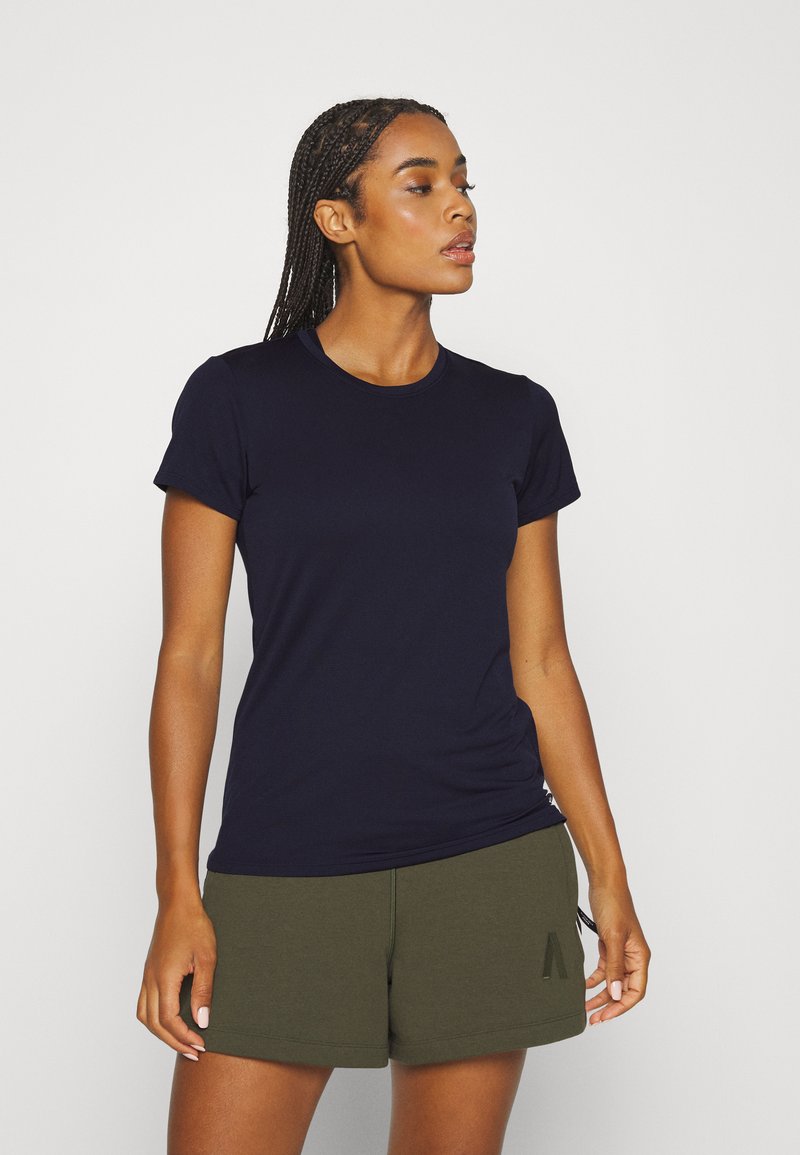 Camiseta de manga corta color azul marino en tejido suave, con un escote redondeado. Combinada con pantalones cortos color verde oliva, que destacan un look casual.