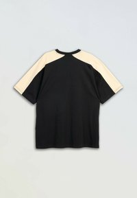 Czarny t-shirt z krótkim rękawem z beżowymi rękawami raglanowymi i beżowym panelem w górnej części ramienia, położony na jasnym tle.