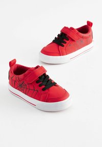 Baskets rouges avec un extérieur en cuir, design en toile d'araignée noire et semelle blanche contrastante. Dotées de lacets noirs et d'une sangle Velcro.