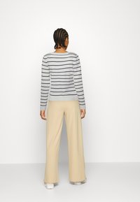 Randig långärmad tröja i ljusblått och marin, i kombination med beige vida byxor. Mjuk textur, avslappnad passform, rund halsringning.