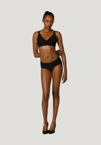 Soutien-gorge sans fil noir et bas de bikini assorti, tous deux avec une texture lisse. Le soutien-gorge présente un design en V, complété par des culottes taille haute.