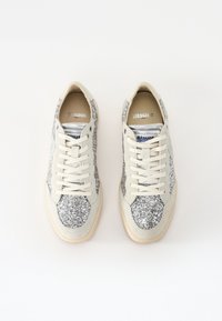 Sneakers glitterati con tomaia in pelle bianca e pannelli in glitter argento, suole beige e lacci bianchi. Dettaglio di cuciture rinforzate.