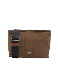 Bolso de hombro de lona marrón con superficie texturizada, correa negra ajustable y pequeño detalle de logo en blanco. Cuenta con múltiples bolsillos para organización.