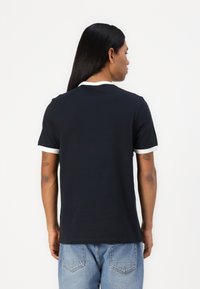 Polo à manches courtes bleu marine avec col et bord des manches blancs, en tissu doux, présentant une coupe décontractée et une texture lisse.