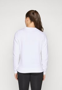 Sweatshirt blanc en mélange de coton avec un col rond, des manches longues et des poignets à côtes, vu de l'arrière. Texture lisse sans motifs.