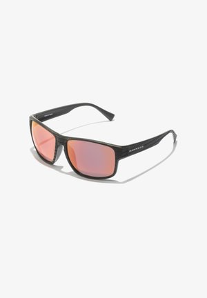 Mustad mustreizikate raamiga mustad prillid, oranžikate läätsede ja voolujoonelise disainiga. Küljes on logoga, millel on kiri "Valmistatud Hispaanias."