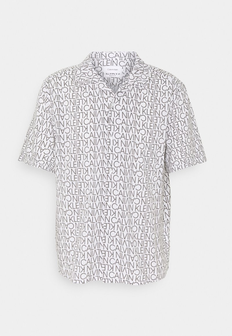 Polo blanc à manches courtes avec imprimé texte noir "Calvin Klein" en toutes orientations et col à boutons.