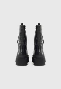 Schwarze Lederstiefeletten mit einer robusten Sohle, Reißverschluss hinten und geschwungenen Seiten für eine markante Silhouette.
