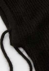 Teren din țesătură neagră, tricotată, cu un model texturat, având fire subțiri și lejere. Materialul pare moale și pufoasă.