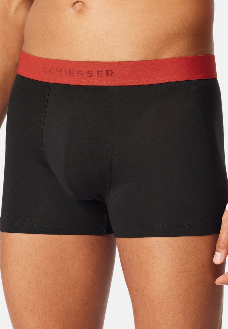 Boxer in cotone nero con elastico rosso sulla vita con il logo "SCHIESSER". Design aderente e texture morbida.