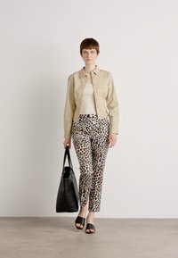 Veste beige avec des détails plissés, haut crème, pantalon à imprimé léopard, sac noir et claquettes noires. Tissu lisse, coupe slim, look décontracté.