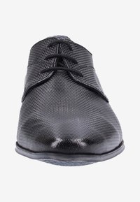 Chaussure habillée en cuir noir texturé avec un bout rond et des lacets noirs, présentée de face sur fond blanc.
