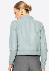 Lichtblauwe leren bomberjack met geribbelde tailleband en manchetten. Beschikt over een gladde textuur en een eenvoudig kraagontwerp.