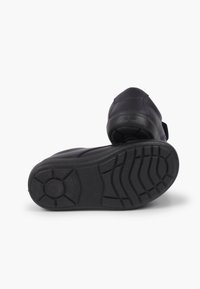 Chaussure bleu marine avec une semelle en caoutchouc texturée, présentant une pointe arrondie et de subtils détails de couture. Le talon est rembourré pour plus de confort.
