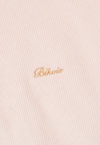 Lyserødt corduroy-stof med lodret ribbing; broderet 'Blkwise' logo i guld på venstre side.