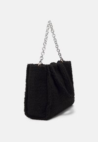 Czarna torebka tote z sztucznego futerka o skręconym wzorze, z trzema srebrnymi łańcuszkami jako uchwytami oraz teksturowaną, puszystą powierzchnią.