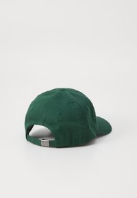 Cappellino da baseball verde in cotone con visiera curva, cinturino regolabile sul retro e un accento in metallo. Presenta una texture liscia e un design a sei pannelli.