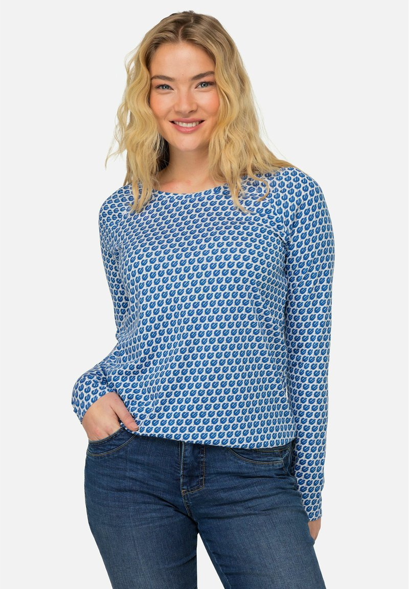 Langarmshirt in Blau mit einem sich wiederholenden Muster aus dunkelblauen Formen, entspannte Passform, weicher Stoff, kombiniert mit einer Jeanshose.