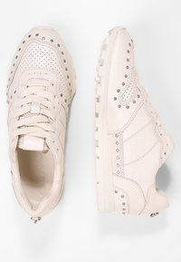 Bílé tenisky vyrobené z hladké kůže, s perforovanými detaily, kovovými akcenty a texturovanou podrážkou. Šněrovací design s logem.