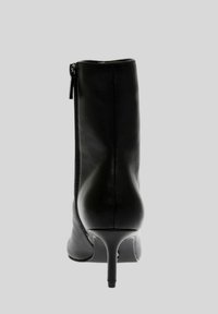 Stivale alla caviglia in pelle nera con punta affusolata, tacco a stiletto sottile e dettaglio con zip laterale. Texture liscia e silhouette elegante.