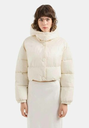 Giacca puffer cropped color avorio con colletto alto, bottoni rotondi e polsini elasticizzati. Texture liscia e imbottita con silhouette oversize.