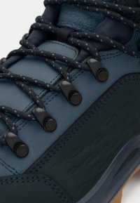 Turistická obuv s kombinací tmavě modrého a námořnického materiálu, strukturovaným povrchem, černými komponenty a modrými detaily na šňůrkách.