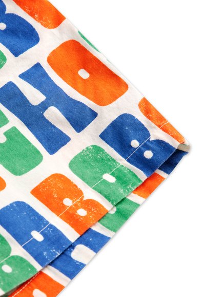 Tissu en coton mettant en avant des lettres audacieuses et multicolores en orange, vert, bleu et blanc, avec une texture douce et une impression légèrement décolorée.