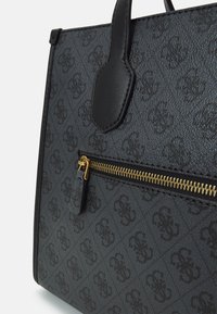 Tmavě šedá vzorovaná taška přes rameno s černými koženými rukojetmi a přední kapsou se zlatým zipem.