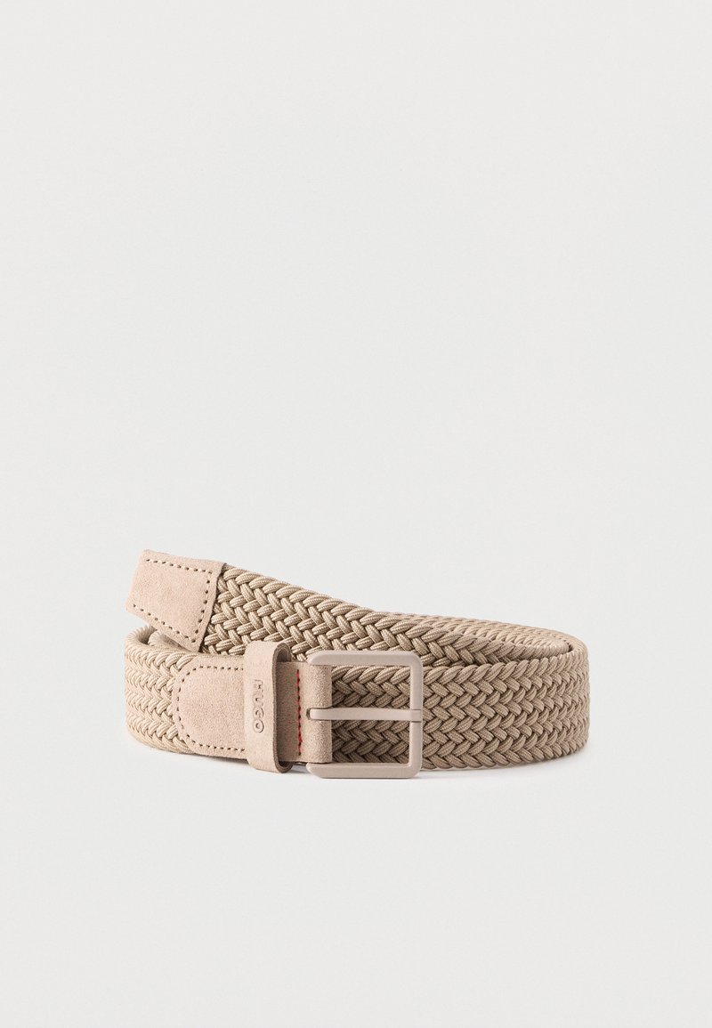 Ceinture en tissu tissé beige avec extrémités en daim et boucle rectangulaire en métal, enroulée sur un fond gris clair.